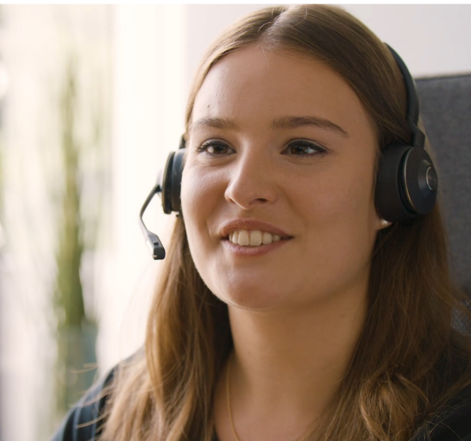 Ein Custom Medical Mitarbeiter trägt ein Headset und grinst.